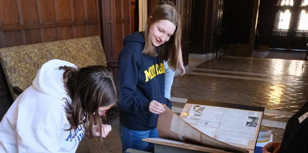 A patron looks through a box of historical postcards. Only the researcher's hands are visible.